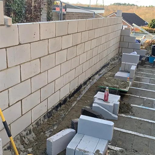 a man with a yellow hose is cleaning a brick wall