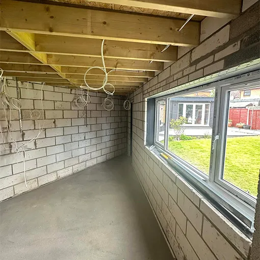 an empty room with a large window and wires hanging from the ceiling