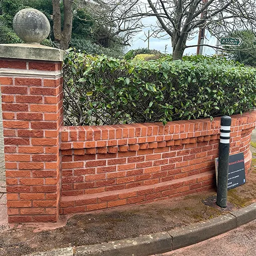 a red brick wall with a clock on top of it